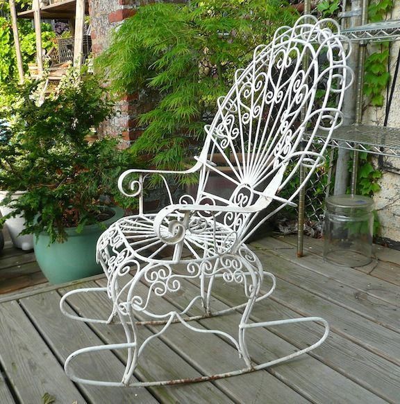 Petite, wrought iron outdoor rocking chair with peacock fan back .