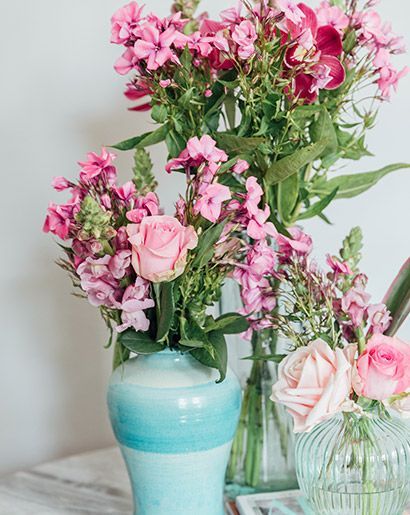 Three vases of different heights with mismatched pink flowers.