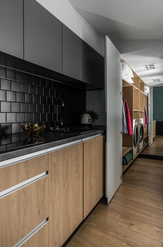 A minimalist kitchen looks chic with stained and black cabinets, a matte black square tile backsplash, and black countertops