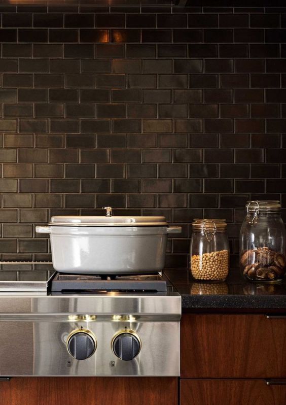 Boldly colored cabinets, gray stone countertops, and black subway tiles for the backsplash create a vintage kitchen