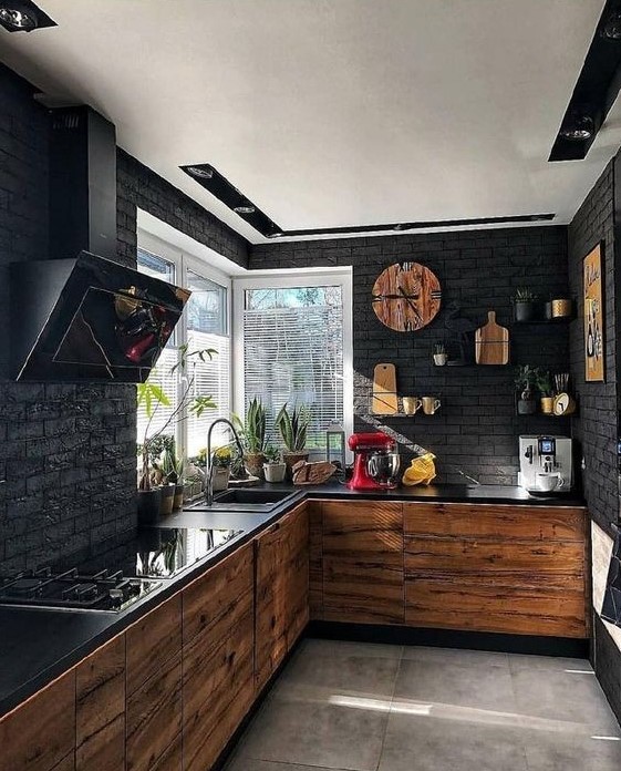 a modern black kitchen with black brick walls, light wooden cabinets, black countertops and an extractor hood
