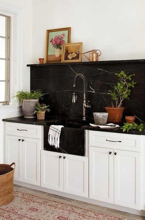 A white farmhouse kitchen is spruced up and made more eye-catching with a black marble backsplash and countertops
