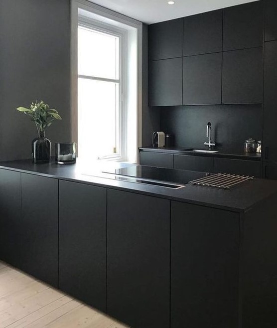 a minimalist black kitchen with sleek cabinets and an elegant kitchen island, as well as a black backsplash and countertops