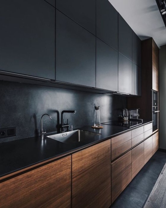 a minimalist kitchen with black and stained sleek cabinets, a black stone backsplash and countertops, and black fixtures