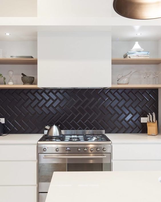 A neutral kitchen with a black herringbone tile backsplash, an extractor hood and open shelving looks bold and contrasting