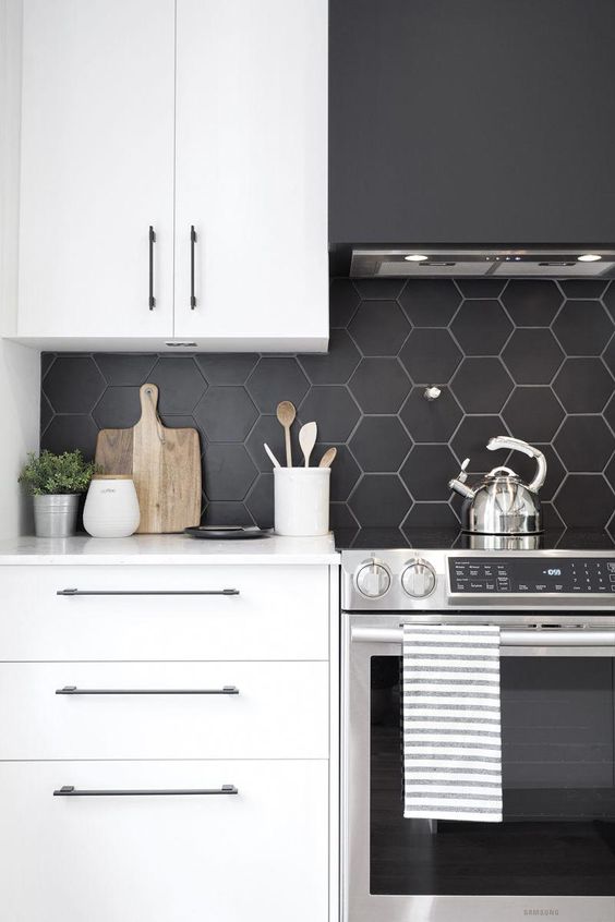 A minimalist white kitchen with a matte black hexagon tile backsplash accented with white grout