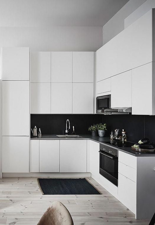 An elegant white kitchen with a large black tiled back wall that creates a contrast and stands out