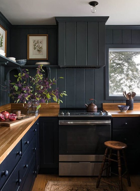 a black farmhouse kitchen with beadboards, light wood countertops and stools, and open shelving
