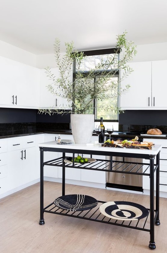 A stylish white kitchen with glossy black tiles and a chalkboard backsplash, a black and white kitchen island is very chic