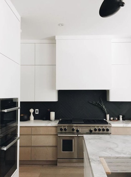 A stylish, minimalist kitchen with light stained cabinets, white upper cabinets, a matte black herringbone backsplash and white quartz countertops