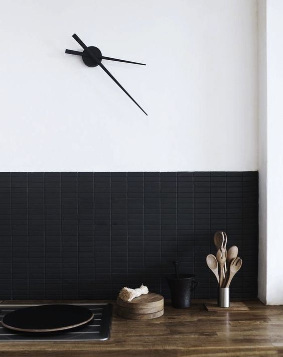 A super modern backsplash with matte black long and narrow tiles contrasts the bright butcher block