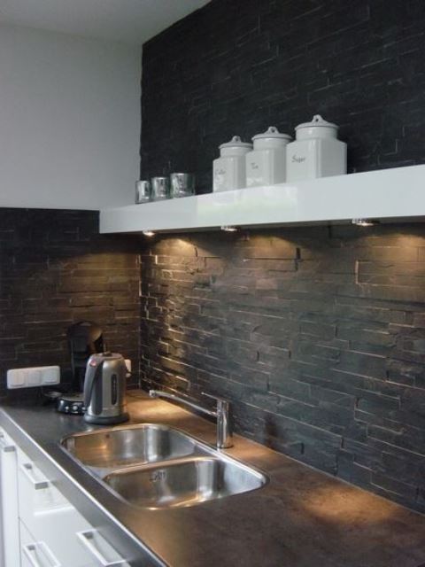 A black faux stone backsplash with additional lights is a cool and stylish idea for a modern kitchen