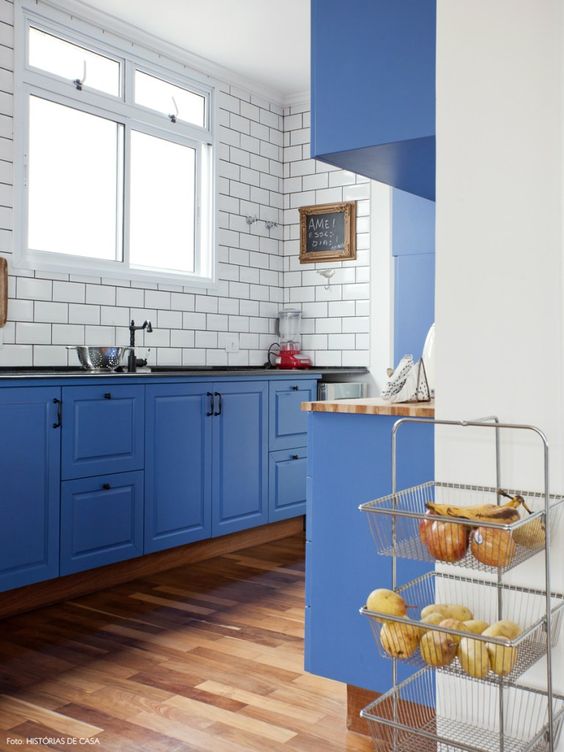 a bold blue kitchen with white subway tiles and black grout that stands out