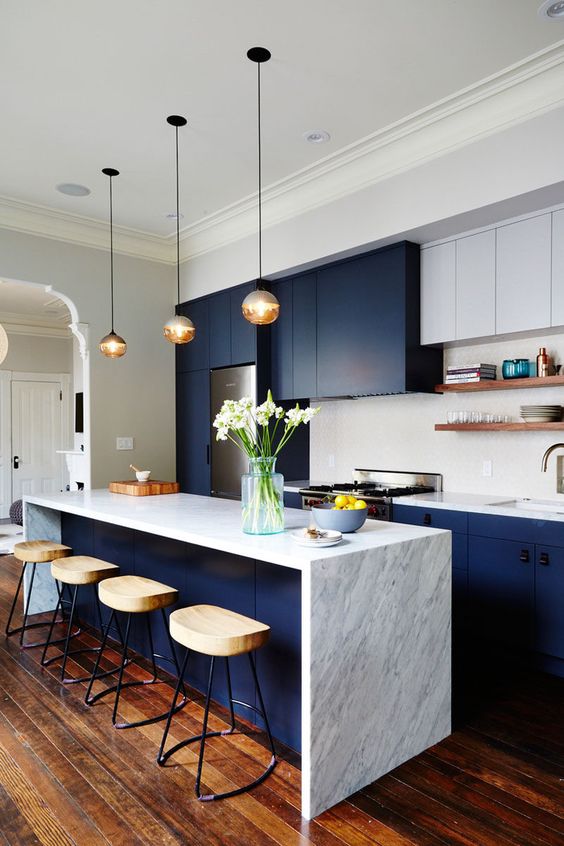 a dark blue modern elegant kitchen with white marble and white cabinets