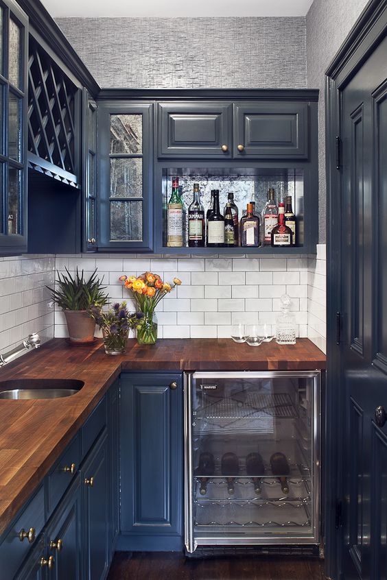 A small dark blue kitchen with a countertop made of saturated wood looks chic