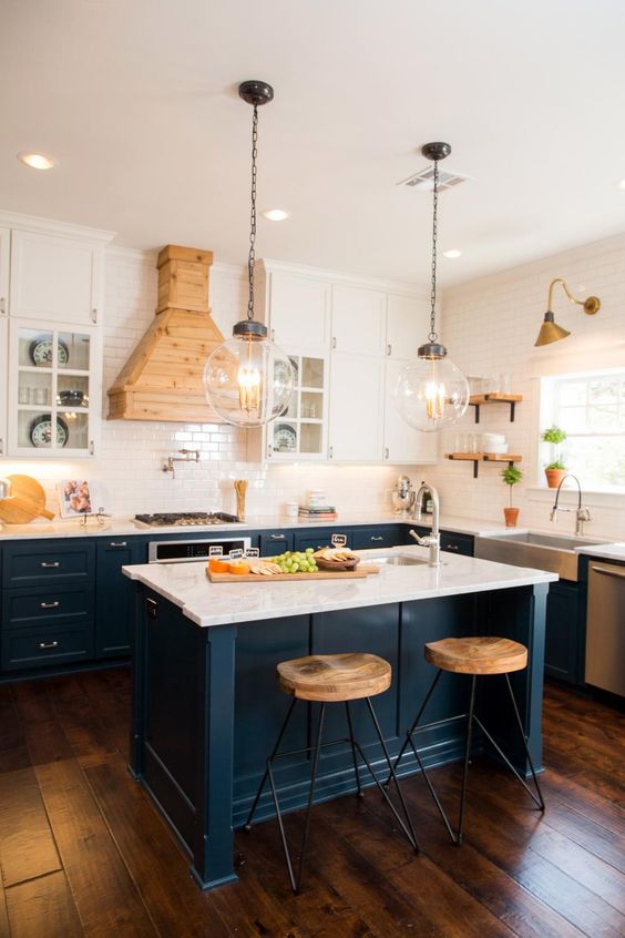 Dark blue kitchen cabinets with marble countertops and hanging white cabinets