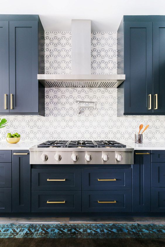 Dark blue cabinets with brass handles and mosaic tiles look very eye-catching