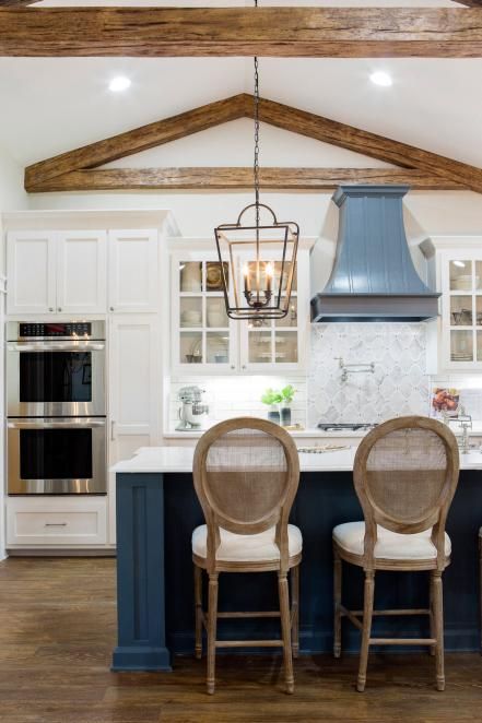 A dark blue kitchen island stands out in the white kitchen cabinets
