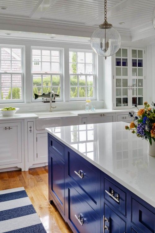 a white kitchen with a bright blue kitchen island reminiscent of the sea theme