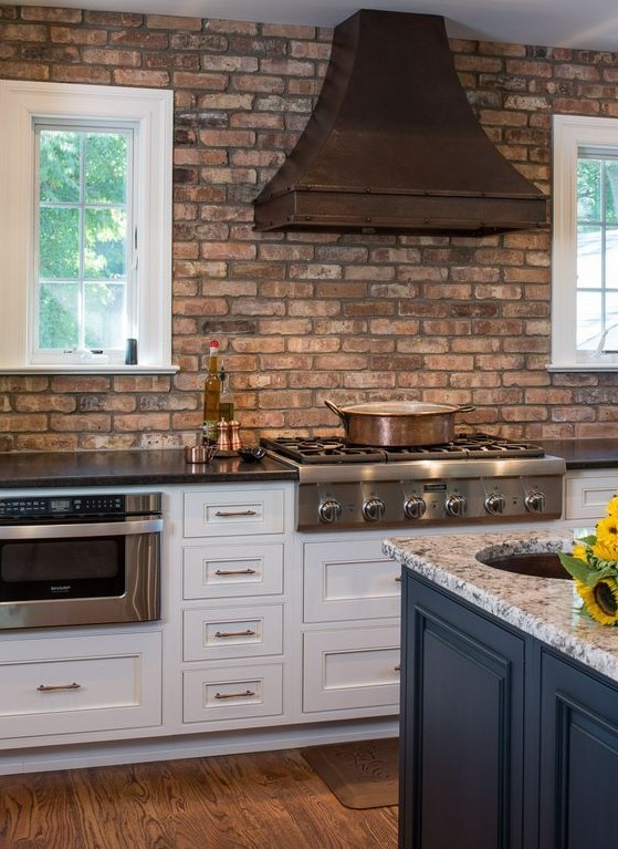 A shabby red birch wall and a darkened metal hood add interest to the space, and stone countertops match
