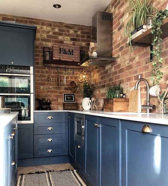 Blue kitchen cabinets with white countertops and red brick walls are a bold contrast idea with a touch of chic