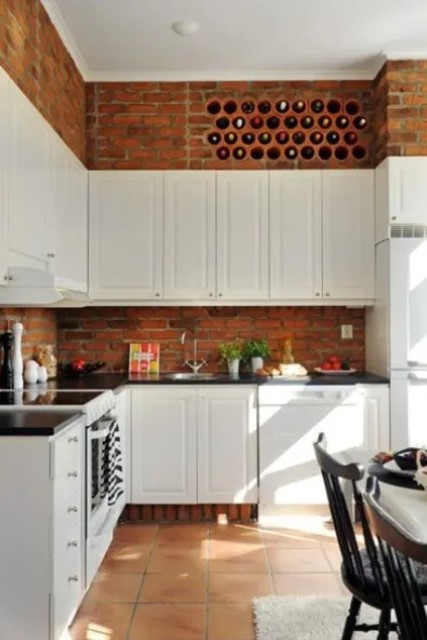 White vintage cabinets and red bricks contrast with each other and add structure to the kitchen