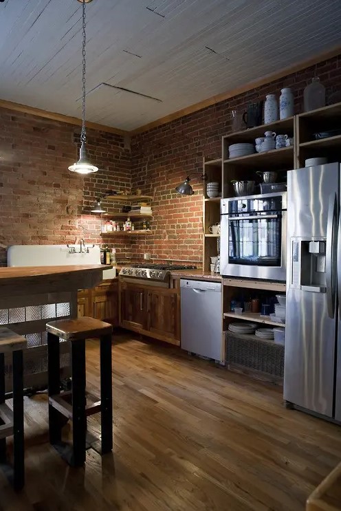 Red brick walls match the richly stained wood and add texture and interest to the kitchen