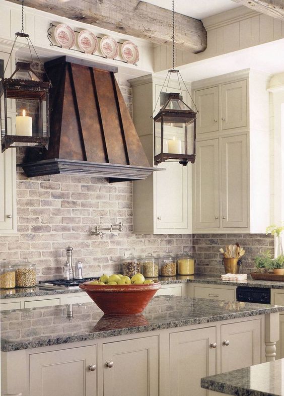 A beautiful white farmhouse kitchen with shaker-style cabinets, a whitewashed brick backsplash, and a vintage metal hood is a beautiful and elegant space to spend time in