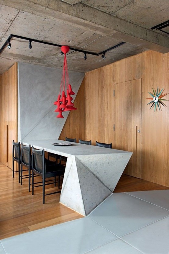 A minimalist and industrial dining area with a sculptural concrete dining table and red pendant lamps above the table is amazing