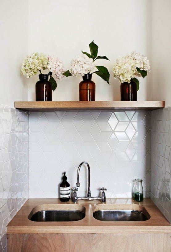 A small kitchen nook with glossy white geometric tiles, plywood recessed sinks and a built-in wooden shelf is amazing