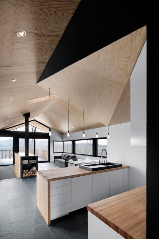 A unique minimalist kitchen in white, black and light stained wood. A sculptural geometric blanket is a beautiful idea and a stylish statement