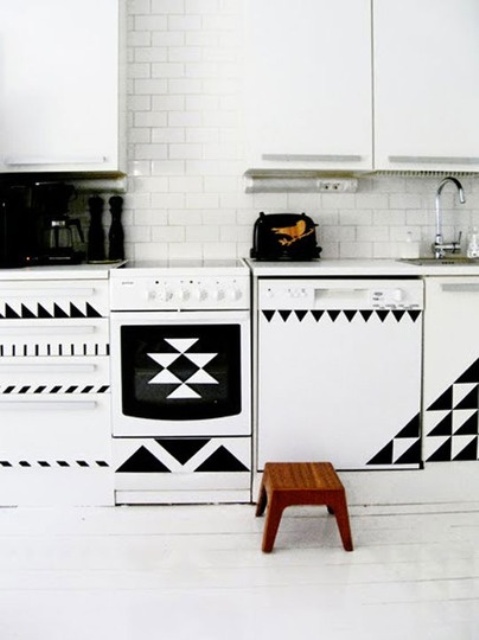 A modern black and white kitchen with geometric details, a white subway tile backsplash and black utensils