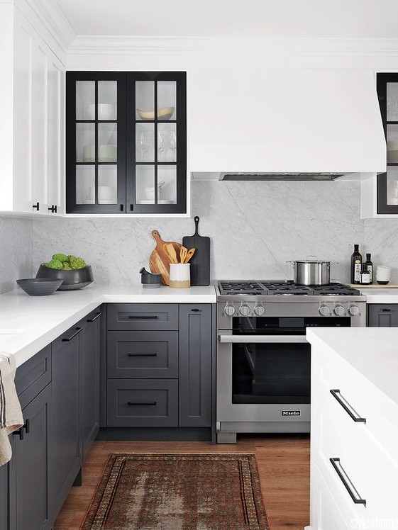 A gorgeous two-tone kitchen with gray and white shaker-style cabinets, white quartz countertops and backsplash, and a boho rug
