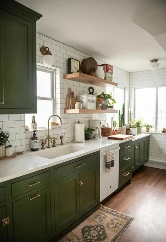 A chic, modern and boho kitchen with olive green shaker cabinets, white stone countertops, white subway tiles and open shelving
