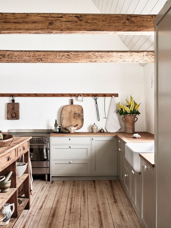 a cozy, modern farmhouse kitchen with strange gray cabinets, stained countertops and wood beams, a stained kitchen island and a stained floor