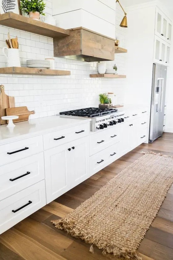 A cozy white modern farmhouse kitchen with a white subway tile backsplash, natural wood accents, and black fixtures