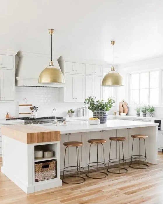 a creamy, modern farmhouse kitchen with shaker-style cabinets, a large island with storage and gold pendant lamps