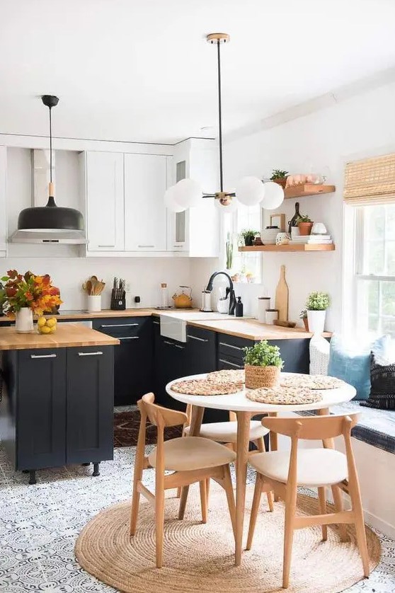 A beautiful modern farmhouse kitchen with white and navy cabinets, butcher block countertops, pendant lamps and black fixtures