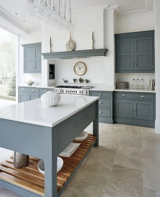 a modern country kitchen with graphite gray cabinets and a kitchen island, white worktops and a built-in extractor hood and a glazed wall