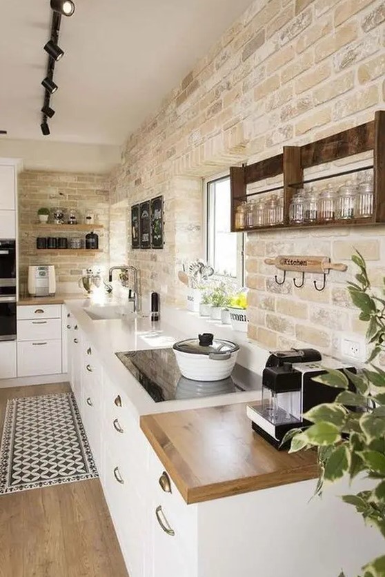 a modern farmhouse kitchen with exposed brick, white cabinets, white and butcher block countertops and laminate flooring