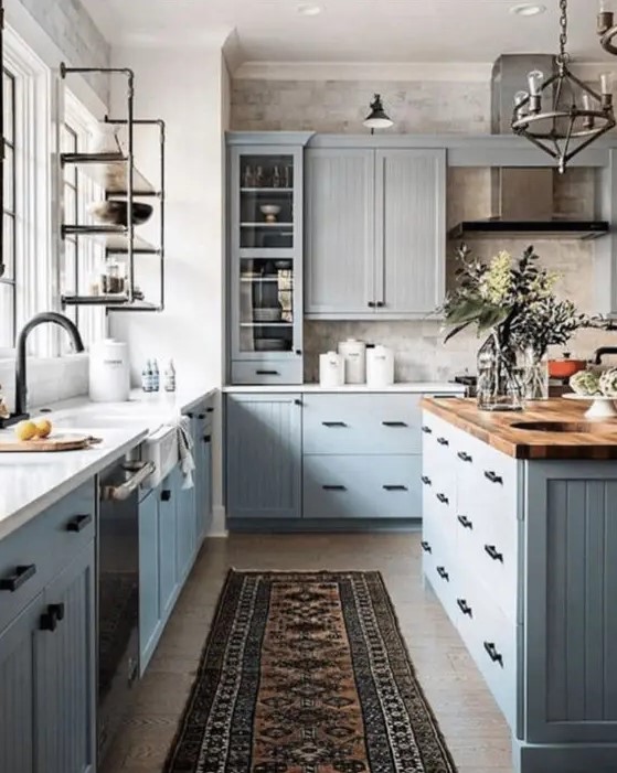 a modern farmhouse kitchen with light gray cabinets, butcher block, white countertops, black fixtures and a vintage metal lamp