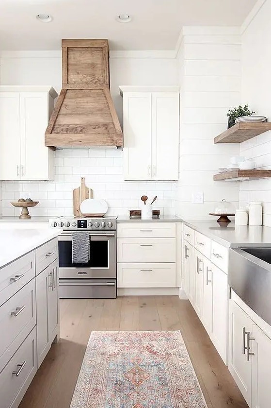a modern farmhouse kitchen with shaker-style cabinets, a white subway tile backsplash, a wood hood, and floating shelves