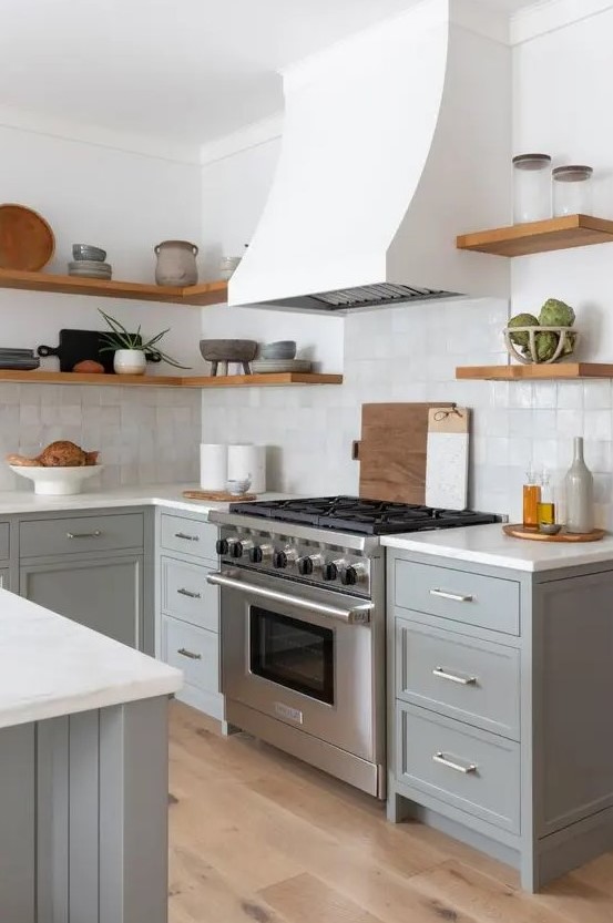 A modern farmhouse kitchen with gray shaker cabinets, white stone countertops, a zellige tile backsplash, and open shelving