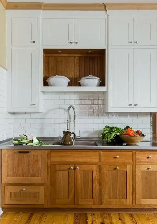 A modern farmhouse kitchen with stained base cabinets and white upper cabinets, a white subway tile backsplash and a metal countertop for a cozy look and maximum functionality