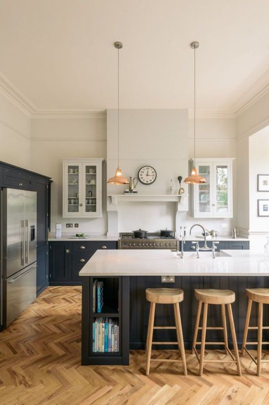 a modern farmhouse kitchen with white and graphite gray cabinets, white stone countertops, pendant lamps and wooden stools
