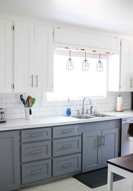 a modern farmhouse kitchen with upper white cabinets, lower gray cabinets, pendant lamps and metallic accents here and there