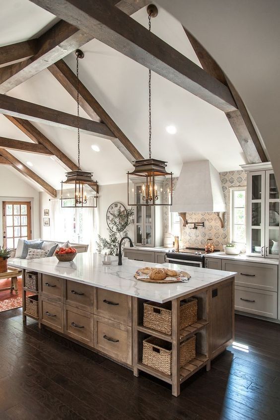 a modern farmhouse kitchen with white shaker-style cabinets and a stained kitchen island, a printed tile backsplash, and chic pendant lamps
