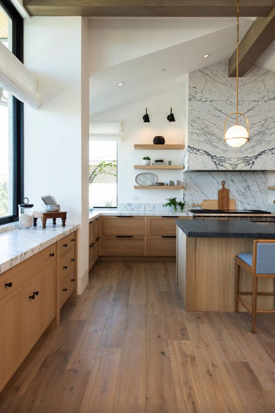 a stylish, modern farmhouse kitchen with stained base cabinets, a large island, marble countertops and a splashback