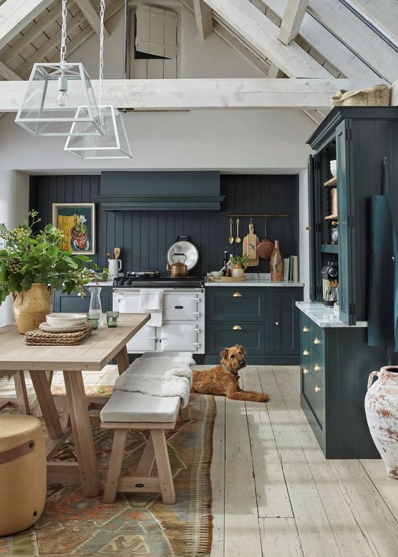 A teal modern farmhouse kitchen with a beadboard backsplash, white stone countertops and a small wooden dining set