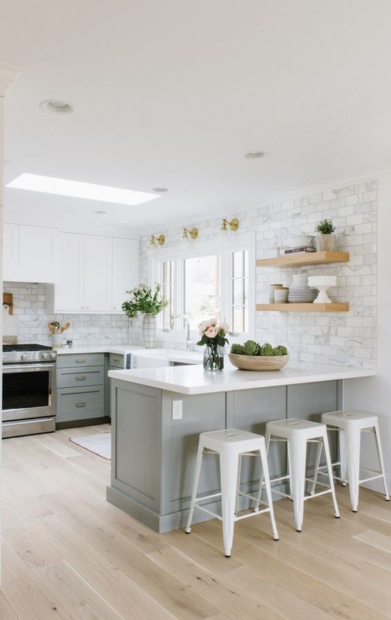 a two-tone modern farmhouse kitchen with white and gray cabinets, open shelving, white marble tiles and metal stools
